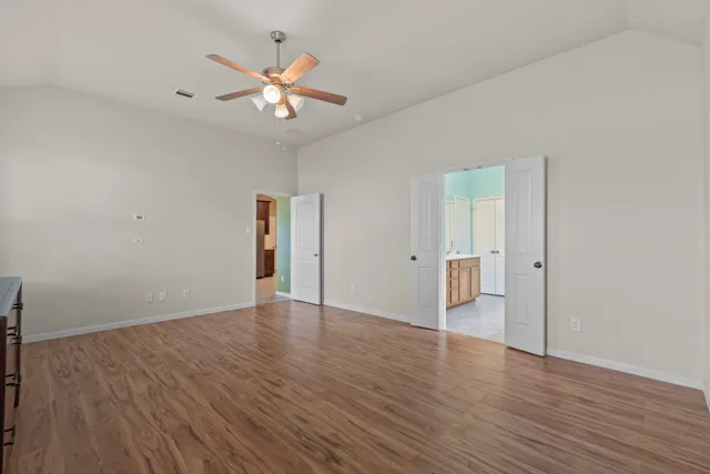 an empty room with wooden floor and a ceiling fan