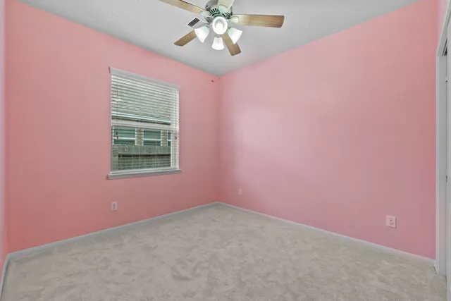an empty room with a chandelier fan and windows