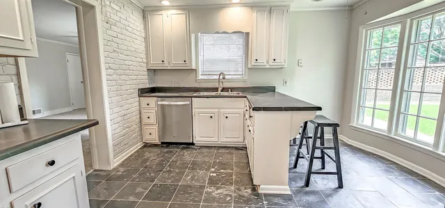 a kitchen with granite countertop white cabinets and stainless steel appliances