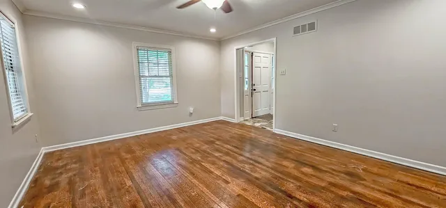 a view of empty room with wooden floor and fan