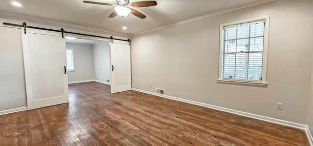 a view of an empty room with wooden floor and a window