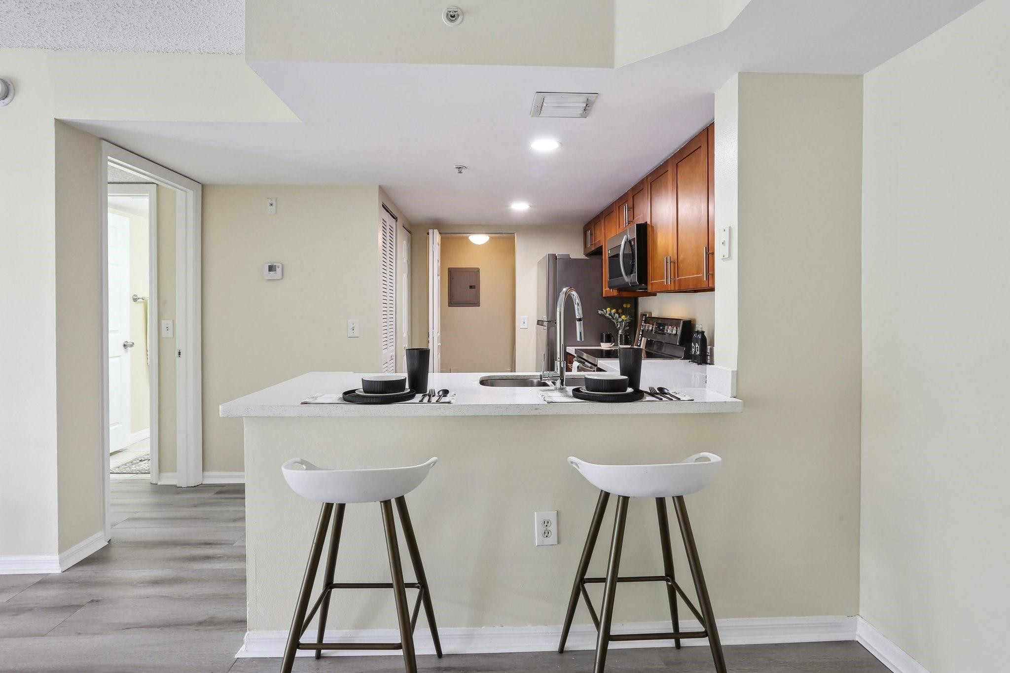 5051 Wiles Road, Unit 201 Coconut Creek, FL 33073 - Photo 1 of 41 a view of a kitchen with kitchen island dining table and wooden floor