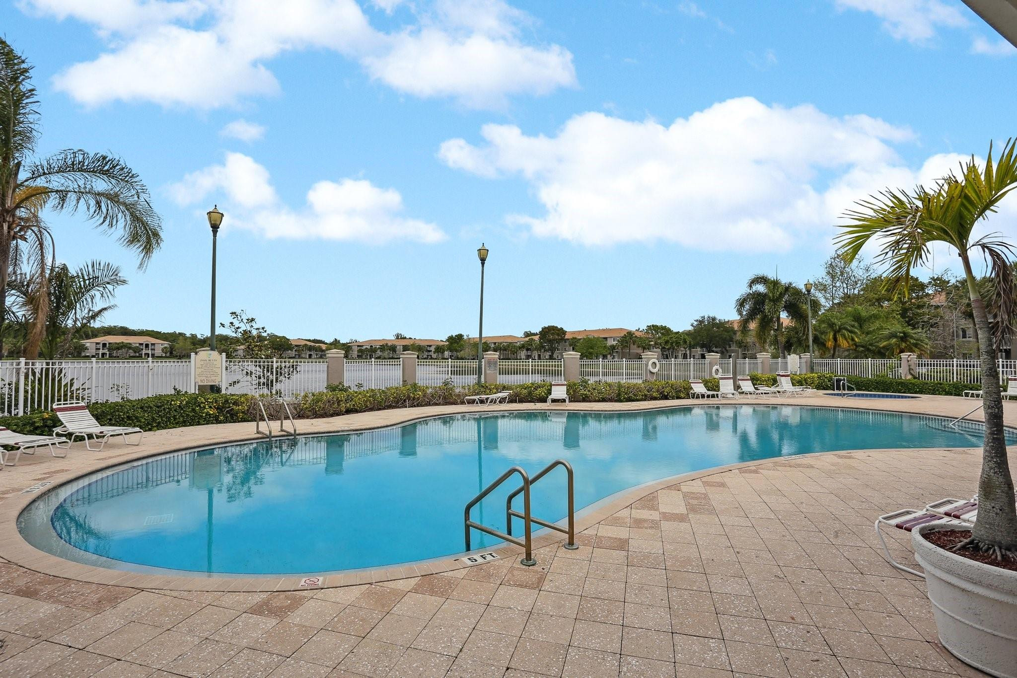 5051 Wiles Road, Unit 201 Coconut Creek, FL 33073 - Photo 38 of 41 a view of a swimming pool with a lake and trees in the back