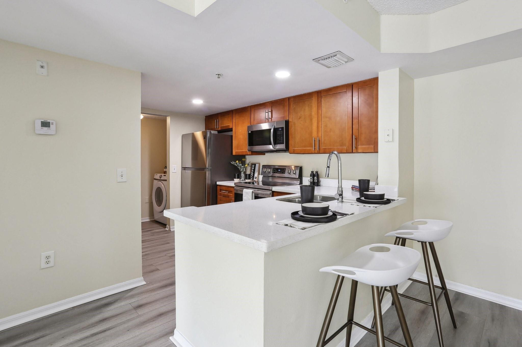 5051 Wiles Road, Unit 201 Coconut Creek, FL 33073 - Photo 4 of 41 a kitchen with a sink a stove and chairs with wooden floor