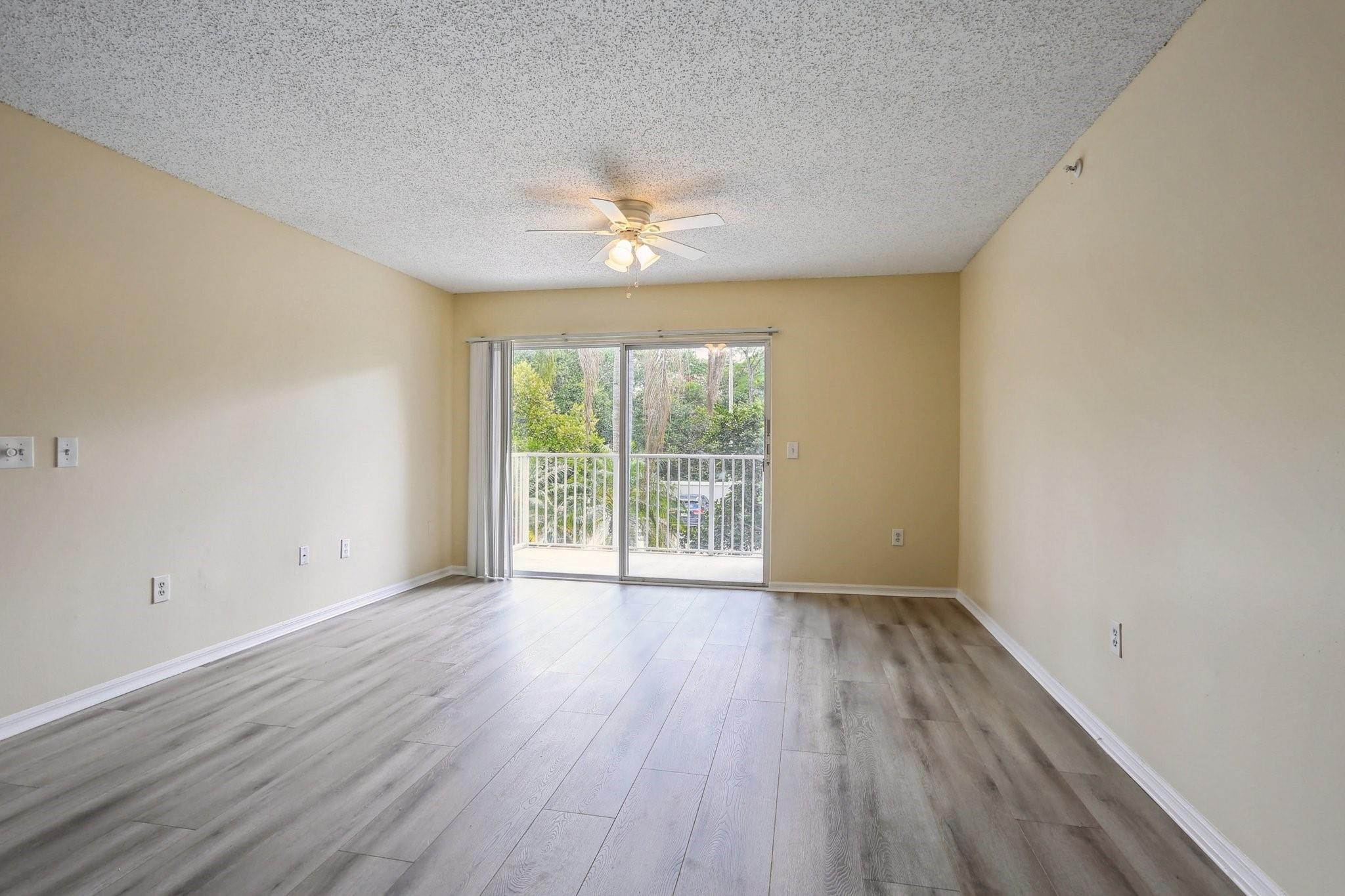 5051 Wiles Road, Unit 201 Coconut Creek, FL 33073 - Photo 9 of 41 a view of an empty room with wooden floor and a window