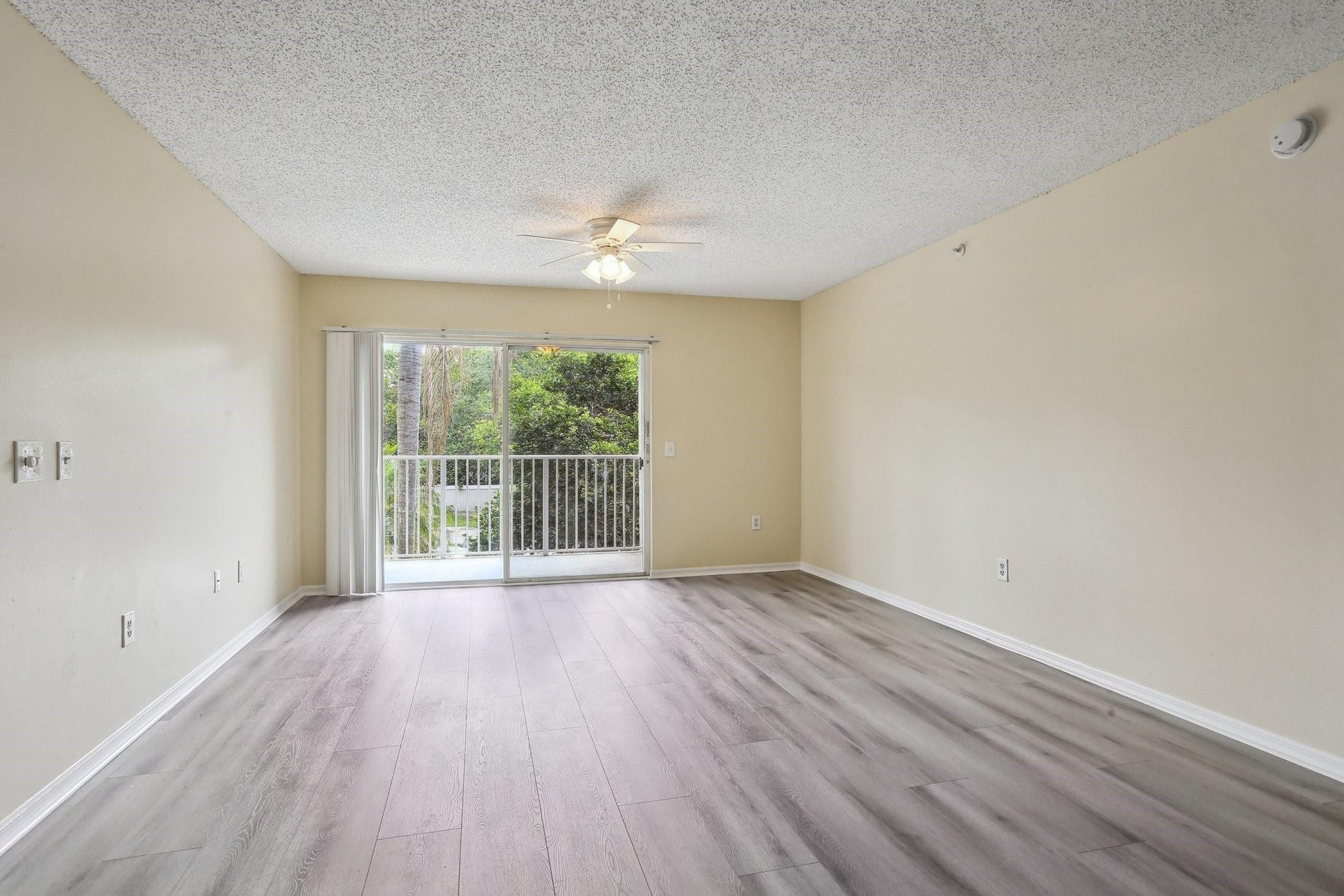 5051 Wiles Road, Unit 201 Coconut Creek, FL 33073 - Photo 10 of 41 a view of an empty room with wooden floor and a window