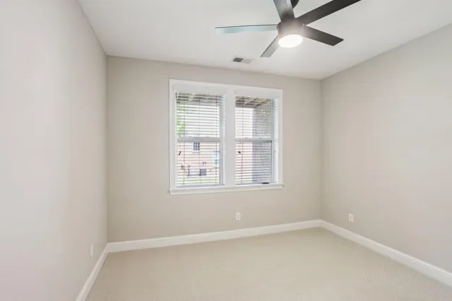 an empty room with a window and a fan