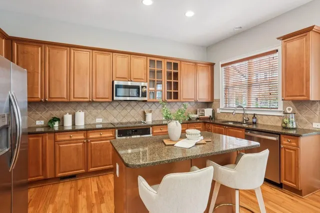 a kitchen with stainless steel appliances granite countertop a stove top oven a sink dishwasher and cabinets with wooden floor