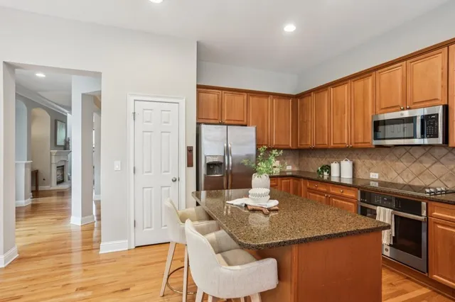 a kitchen with stainless steel appliances granite countertop a refrigerator a stove a sink dishwasher and white cabinets with wooden floor