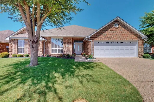 a view of a house with a small yard plants and large tree