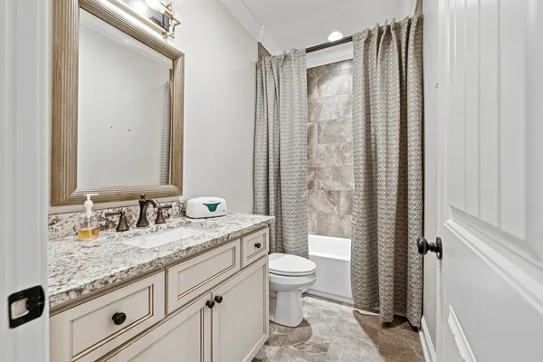 a bathroom with a granite countertop sink toilet mirror and shower
