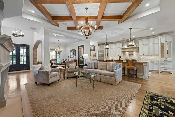 a living room with furniture kitchen view and a chandelier