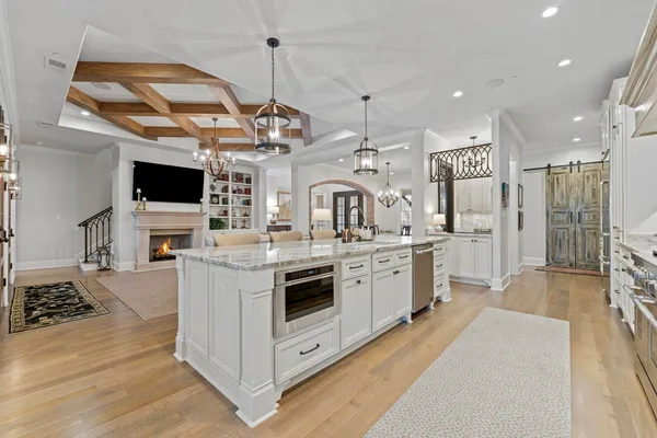 a large kitchen with stainless steel appliances granite countertop a stove and a view of living room