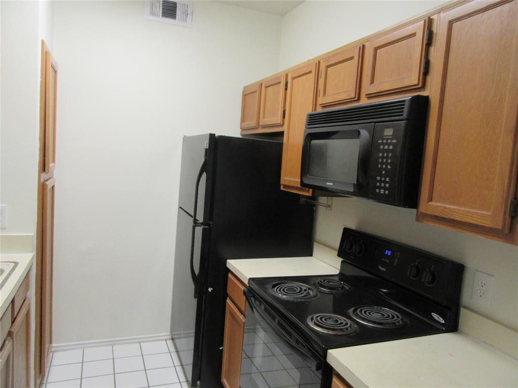 9737 Whitehurst Drive, Unit 39 Dallas, TX 75243 - Photo 2 of 5 a kitchen with a stove and a microwave