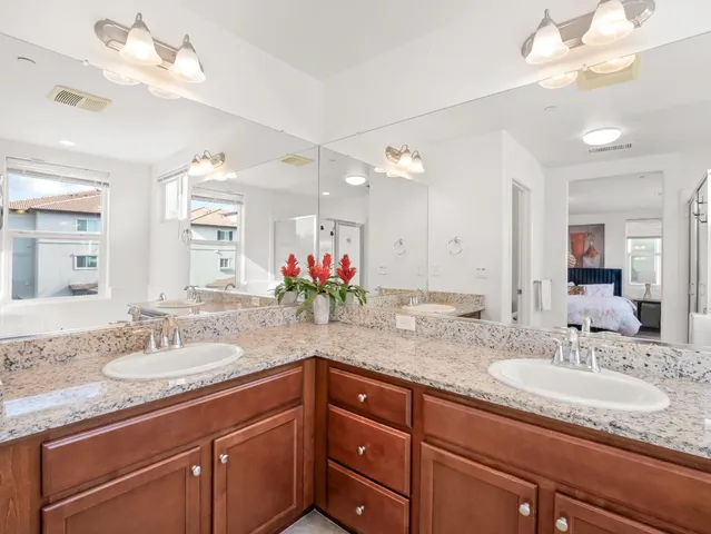 a bathroom with a granite countertop double vanity and a mirror