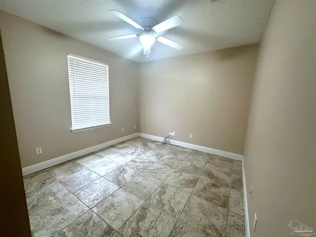 an empty room with a chandelier fan and windows