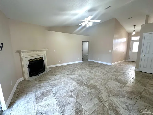 a view of an empty room with wooden floor and a fireplace