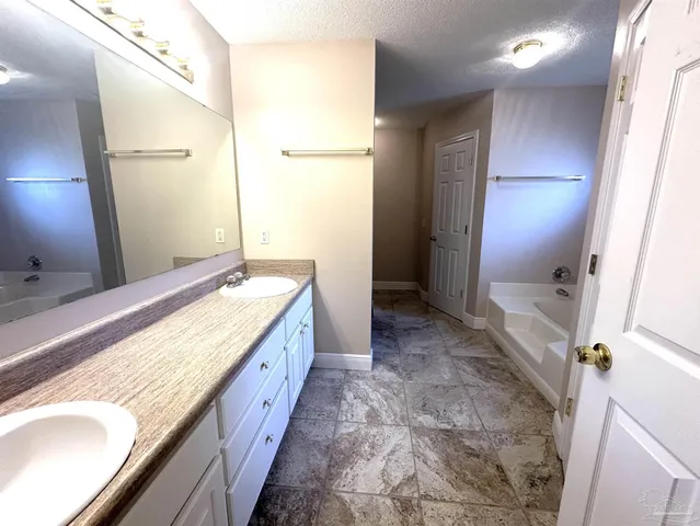 a spacious bathroom with a granite countertop sink a mirror and a shower