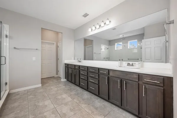 a spacious bathroom with a double vanity sink a mirror and a shower