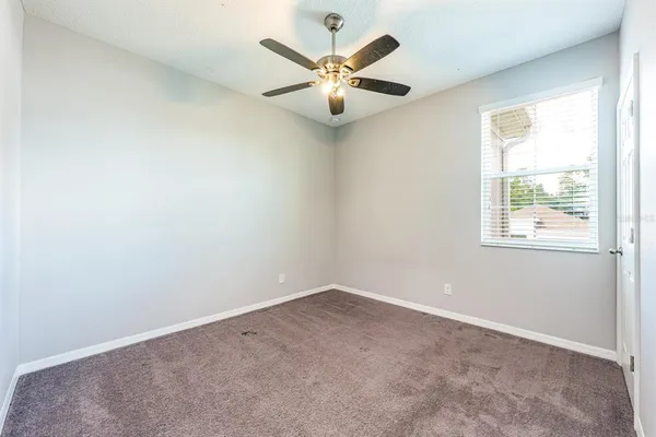 an empty room with window and ceiling fan