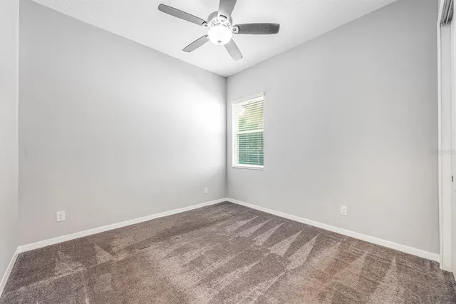 an empty room with a chandelier fan and windows