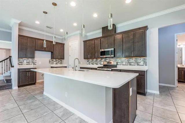 a kitchen with kitchen island stainless steel appliances a sink a stove a microwave a center island and cabinets