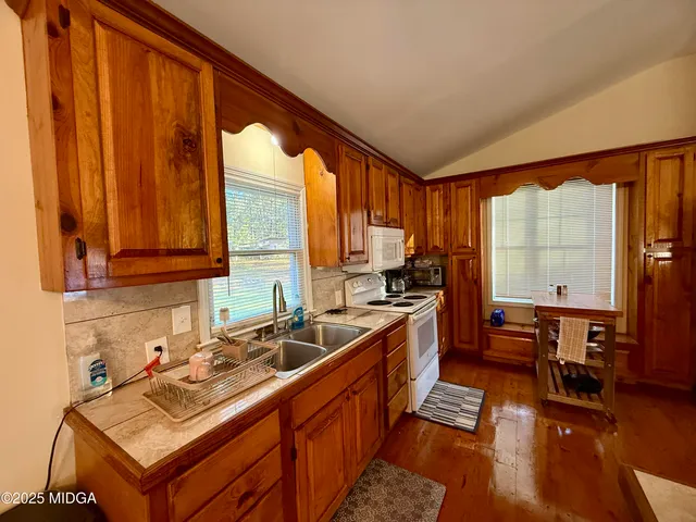 a kitchen with wooden cabinets a sink dishwasher and a stove with wooden floor