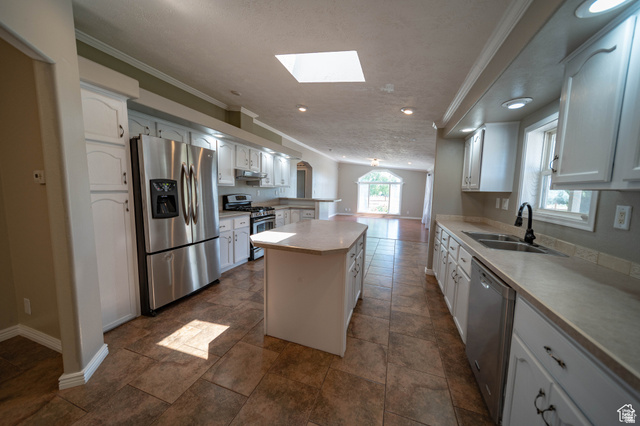 1407 North 1250th Street West Helper, UT 84526 - Photo 9 of 27 Kitchen with stainless steel appliances, a center island, a skylight, crown molding, and white cabinetry