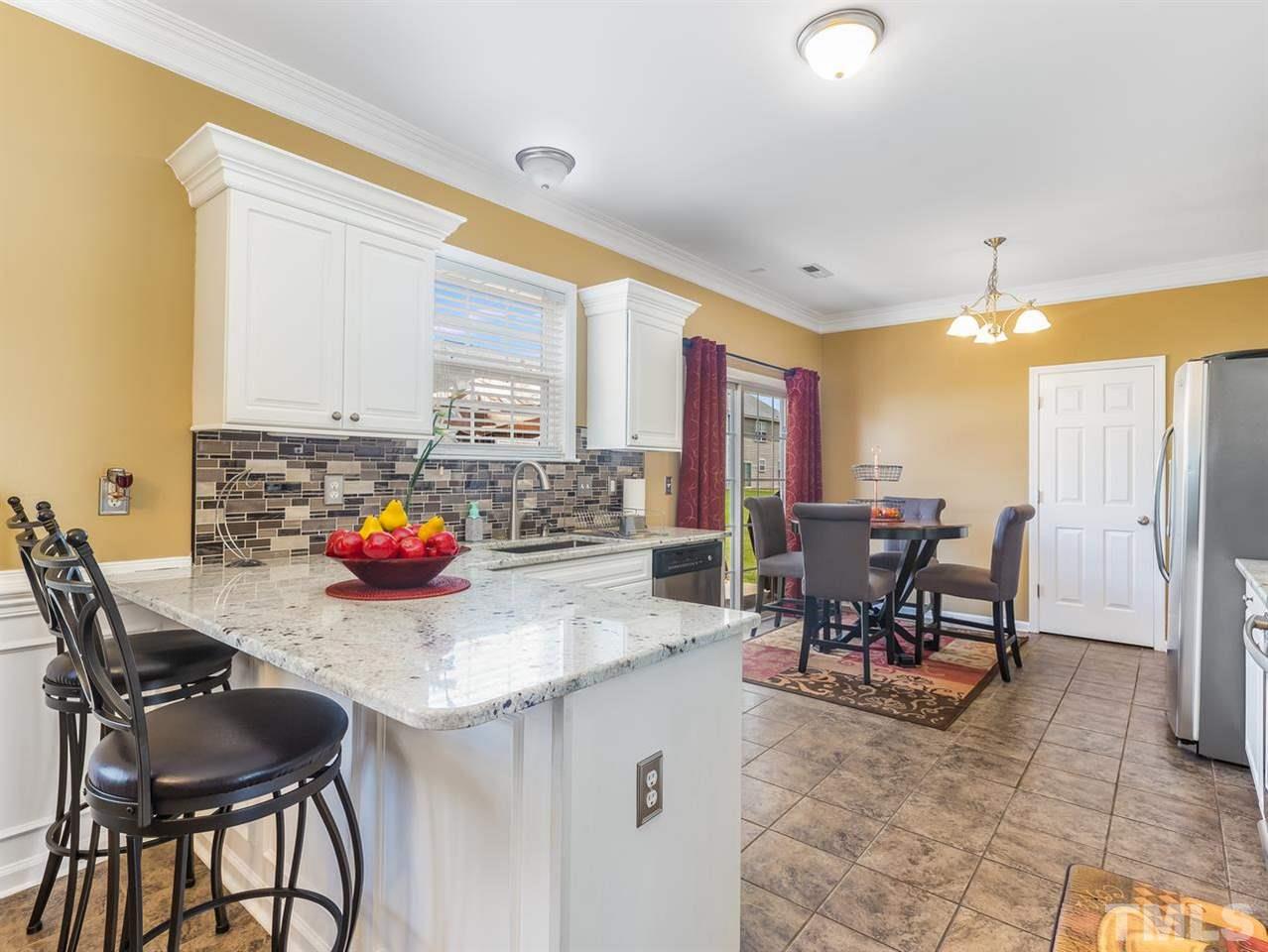 7021 Spanglers Spring Way Raleigh, NC 27610 - Photo 7 of 18 a kitchen with stainless steel appliances kitchen island granite countertop a table chairs and a refrigerator