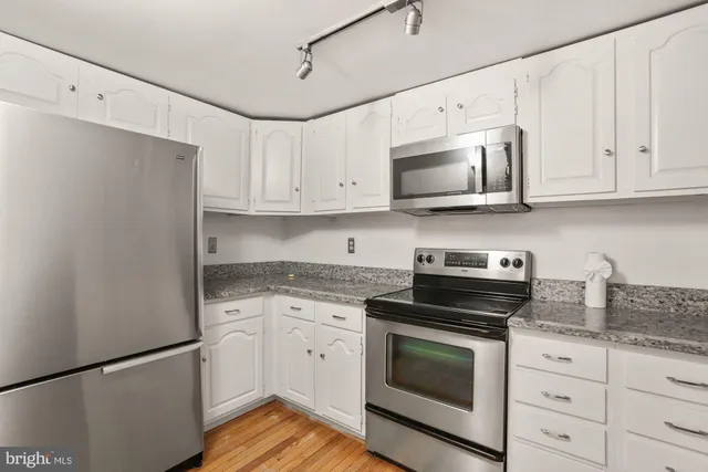 a kitchen with granite countertop white cabinets and stainless steel appliances