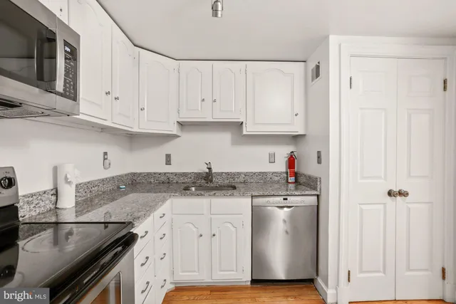 a kitchen with granite countertop a stove sink and cabinets