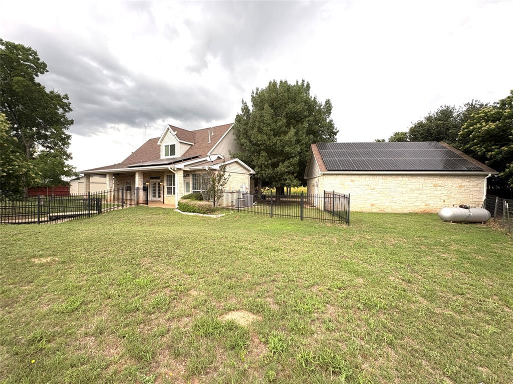 1170 Brazos Loop Gholson, TX 76705 - Photo 30 of 37 Expansive lawn area featuring a two-story residence with a covered porch, stone facade accents, and dormer windows