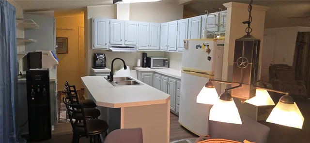 a kitchen with stainless steel appliances a stove a refrigerator and a dining table with wooden floor