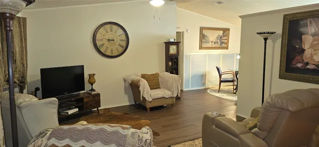 a living room with furniture a clock on the wall and a flat screen tv