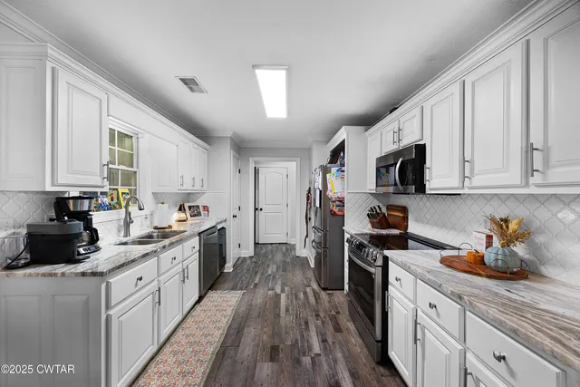 a kitchen with stainless steel appliances a sink dishwasher a stove top oven a refrigerator with cabinets and wooden floor