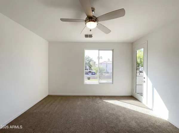 an empty room with windows and ceiling fan