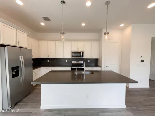 a large kitchen with stainless steel appliances granite countertop a refrigerator a sink a stove and a granite counter top