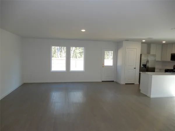 an empty room with windows and chandelier fan