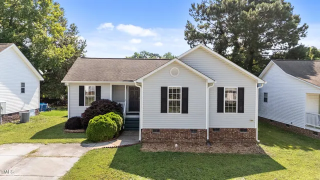 a view of a house with a yard plants and large tree