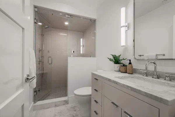 a bathroom with a granite countertop sink a toilet and shower