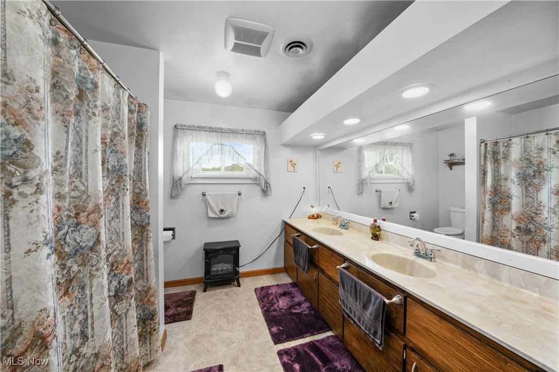 6677 Fee Road Rome, OH 44085 - Photo 21 of 39 Bathroom with a wealth of natural light, vanity, toilet, and a wood stove