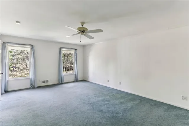 an empty room with windows and fan