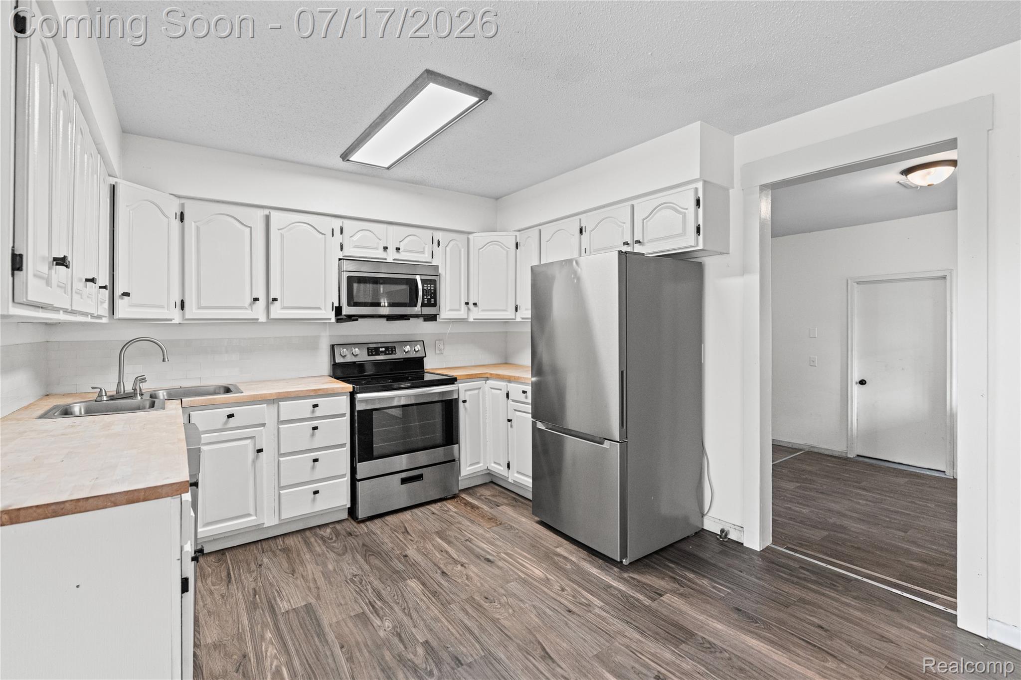 9204 Bray Road Millington, MI 48746 - Photo 2 of 14 Kitchen featuring white cabinetry, wood-finish countertops, stainless steel appliances, and dark wood-finish flooring