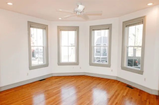 a view of an empty room with a window and wooden floor