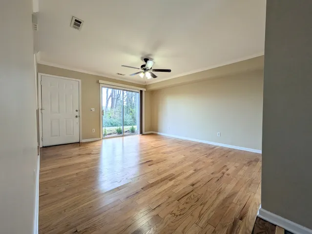 a view of an empty room with wooden floor and a window