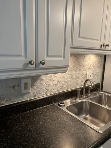 a kitchen with granite countertop a sink and white cabinets