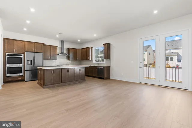 a large kitchen with stainless steel appliances a large counter top a stove and a refrigerator