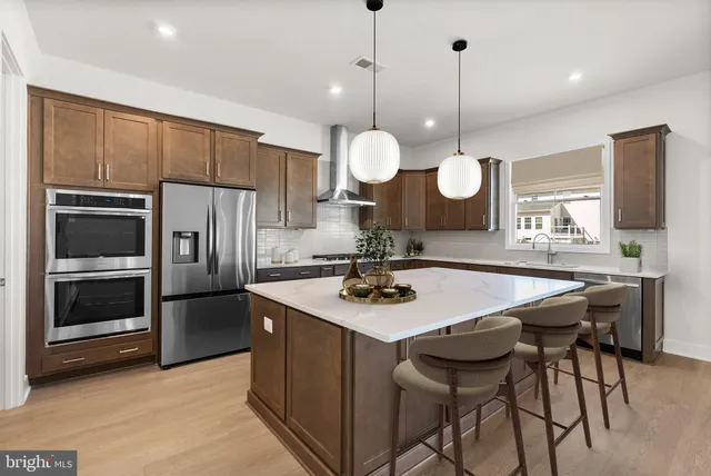 a kitchen with a table chairs stainless steel appliances and wooden floor