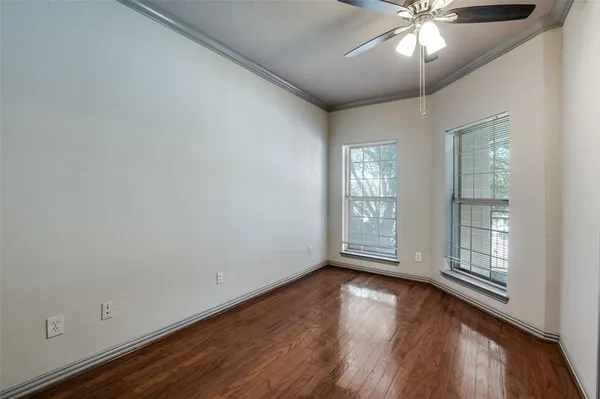an empty room with wooden floor fan and windows