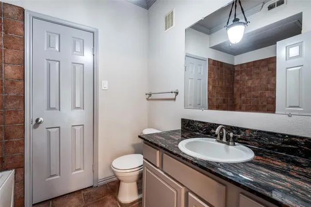 a bathroom with a granite countertop sink a toilet a mirror and shower